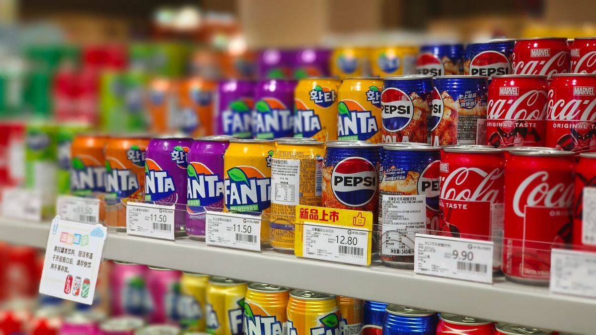 Cans of soft drinks lined up on a retail shelf